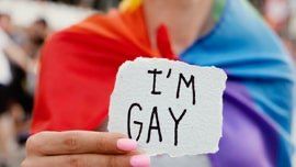 Une femme qui tend une feuille sur laquelle est inscrit "I'm gay"