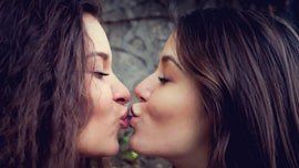 2 women in front of a wall who kiss on the mouth, 2 lesbians who have come out and take responsibility